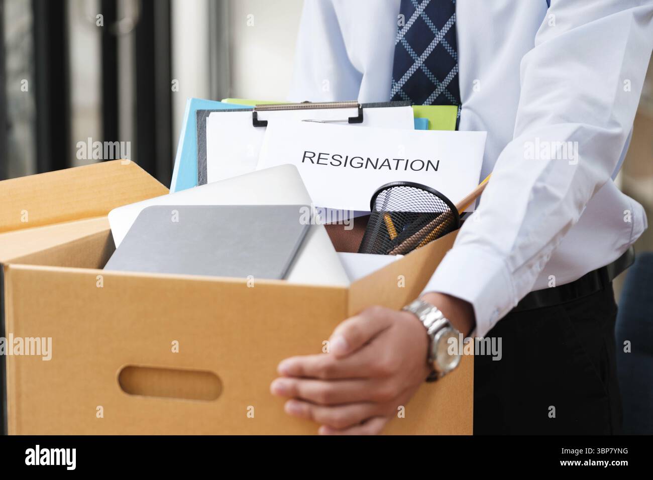 Dipendente maschio che imballa i suoi effetti personali in una scatola di cartone con una lettera di dimissioni, segnalando la sua decisione di abbandonare il lavoro Foto Stock Dipendente maschio che imballa i suoi effetti personali in una scatola di cartone con una lettera di dimissioni, segnalando la sua decisione di abbandonare il lavoro Foto Stock