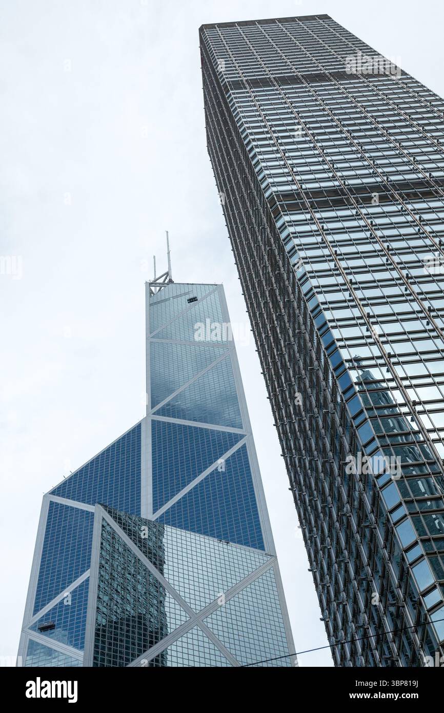 Hong Kong - 15 luglio 2017: La fotografia verticale di due moderni grattacieli si innalza contro il cielo azzurro, mostrando intricati disegni architettonici Foto Stock