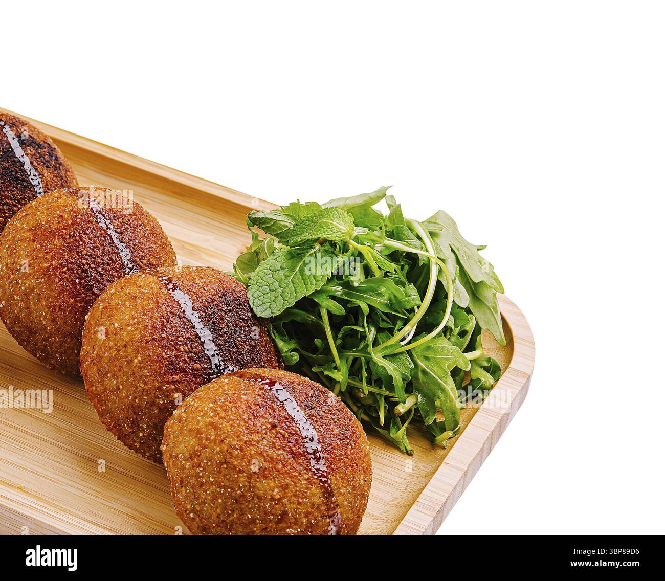 Cibo: Un vassoio di legno contiene diversi spuntini croccanti dorati e una generosa porzione di erbe verdi fresche. Gli spuntini sono rotondi con una glassa lucida, Foto Stock