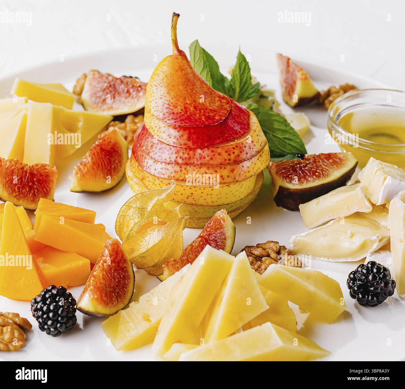 Cibo, elegante disposizione di vari formaggi, fichi freschi, pera e noci su un piatto di ceramica Foto Stock