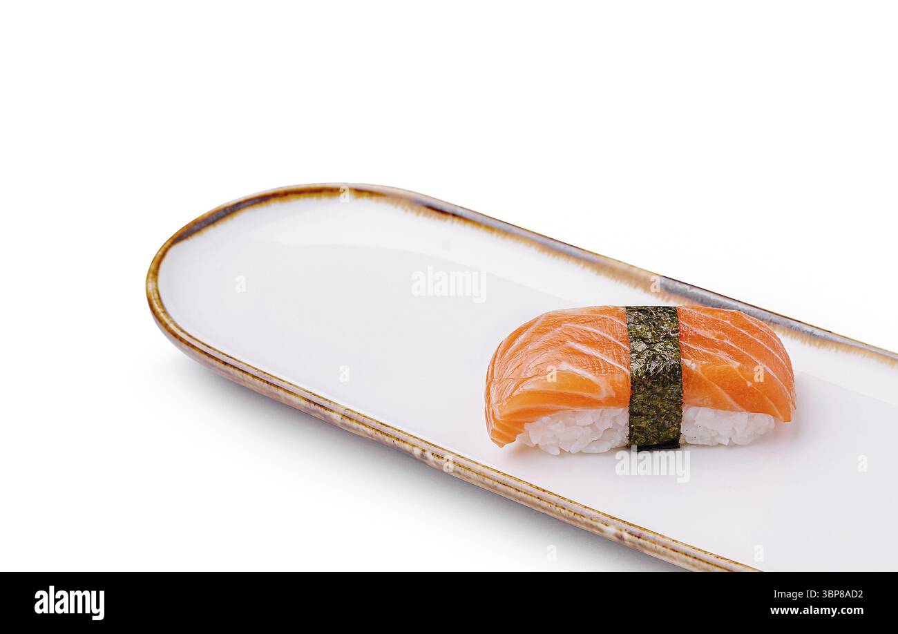 Cibo: Un solo pezzo di nigiri di salmone è presentato splendidamente su un piatto bianco ed elegante. Il salmone lucido contrasta con il riso e le alghe, invitate Foto Stock