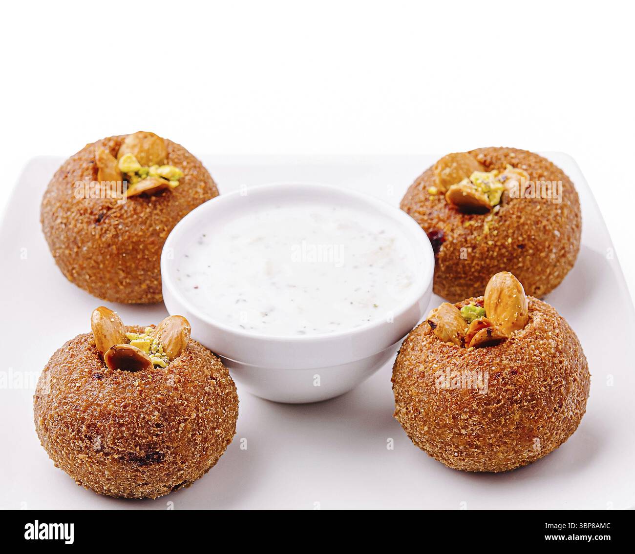 Cibo, quattro croccanti spuntini rotondi conditi con noci sono seduti accanto a una ciotola di salsa di yogurt fresca. Perfettamente preparati, sono un piacere da condividere in ga Foto Stock