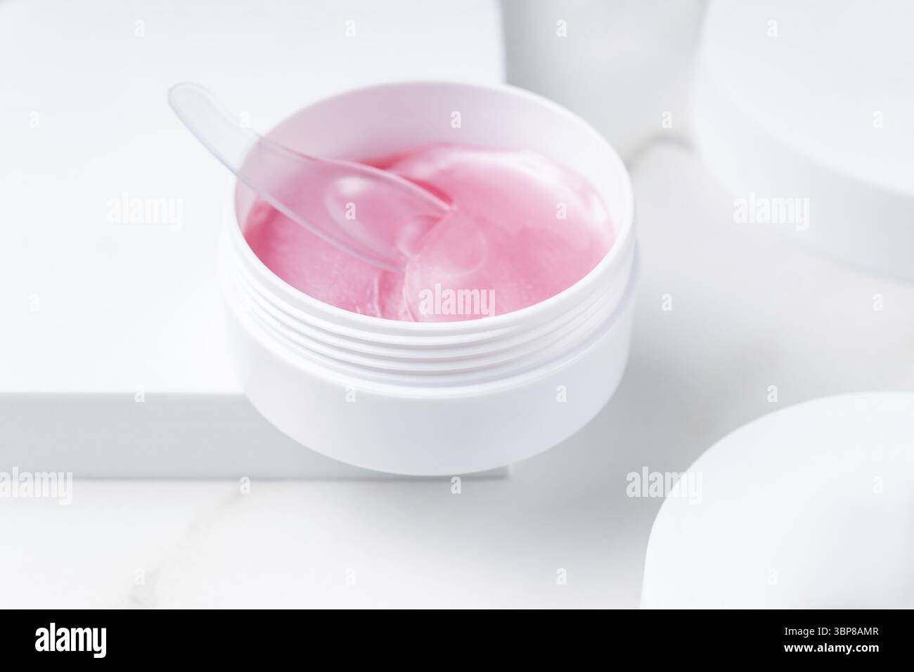 Cerotti di idrogel rosa per la pelle sotto gli occhi sul podio bianco. Presentazione alla moda di cosmetici per la cura della pelle. Routine quotidiana per un trattamento delicato della pelle Foto Stock