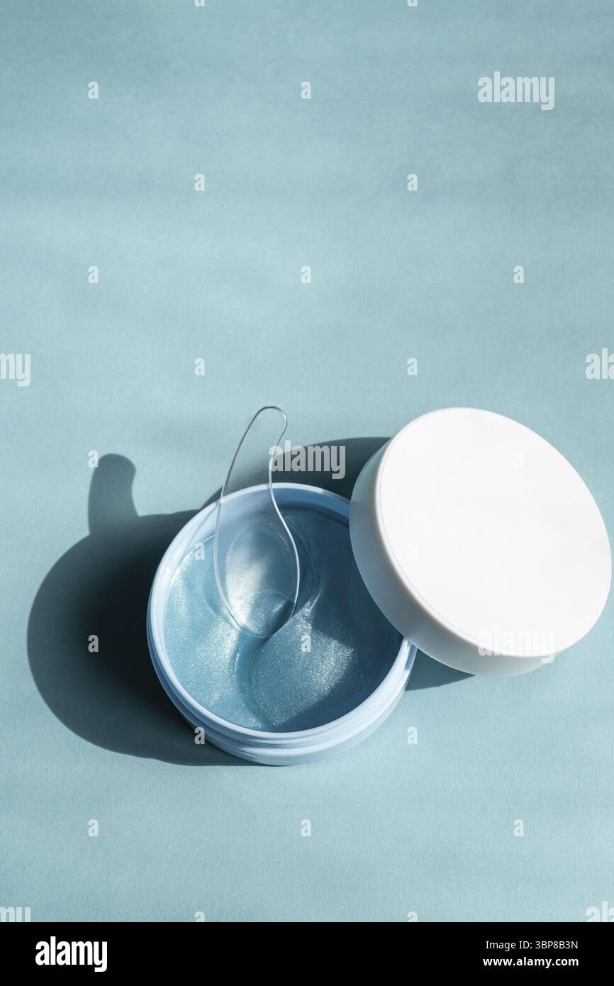Concetto cosmetico moderno. Macchie blu scintillanti per gli occhi del viso in vaso di plastica. Cerotto idrogel. Cosmetici anti invecchiamento e sollevamento. Cura della pelle del viso. Idratazione Foto Stock