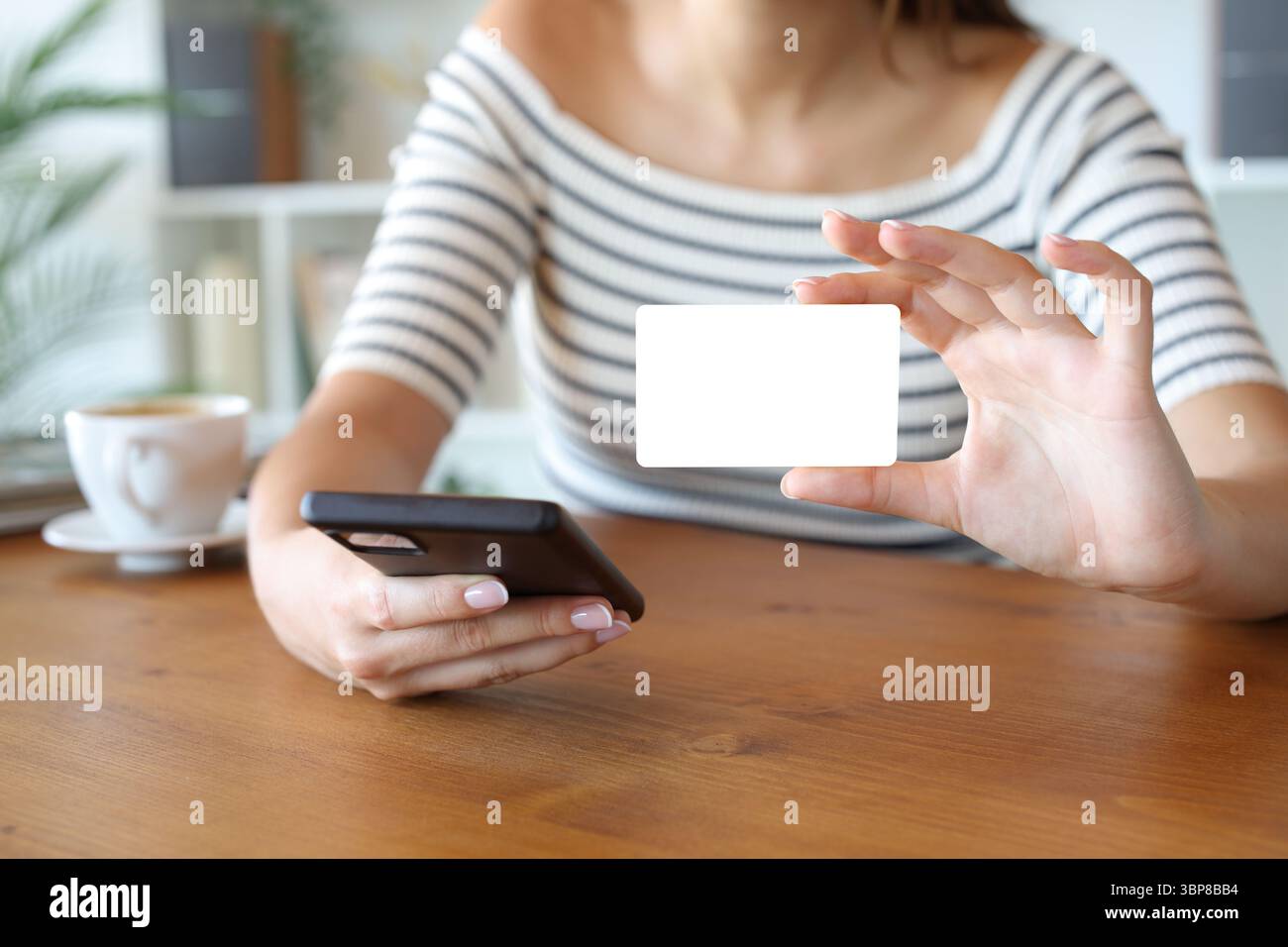 Primo piano di una donna che acquista una mano online con il telefono che mostra una carta di credito vuota a casa Foto Stock