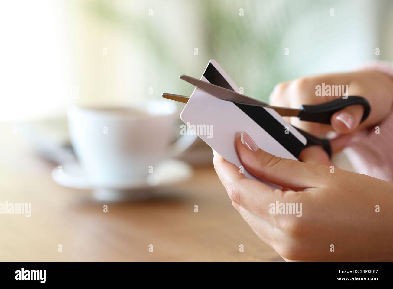 Primo piano di una donna che distrugge la carta di credito tagliando con le forbici a casa Foto Stock