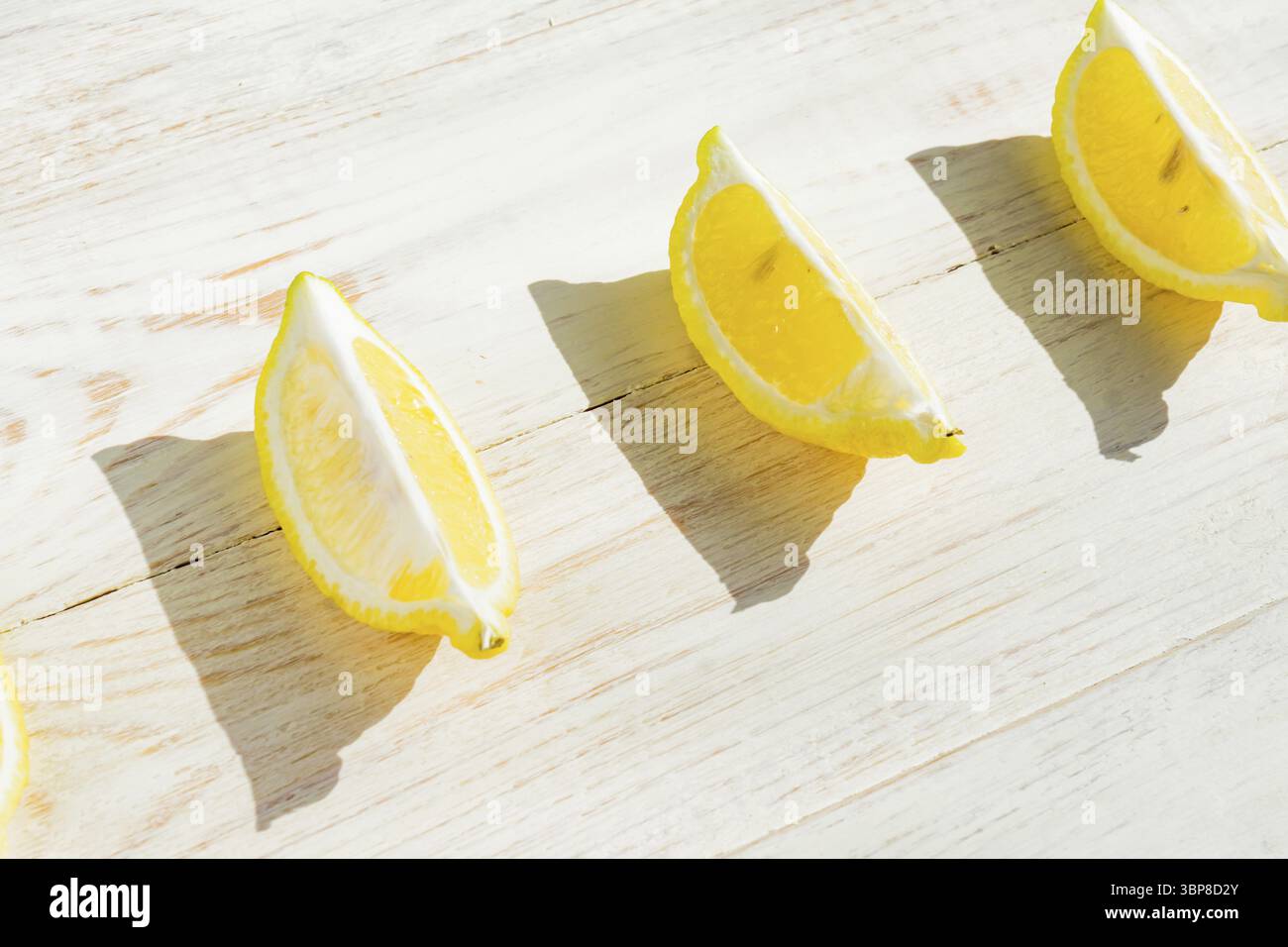 Primo piano di un quarto di limone su un tavolo di legno. Ombre dure in una giornata buia Foto Stock