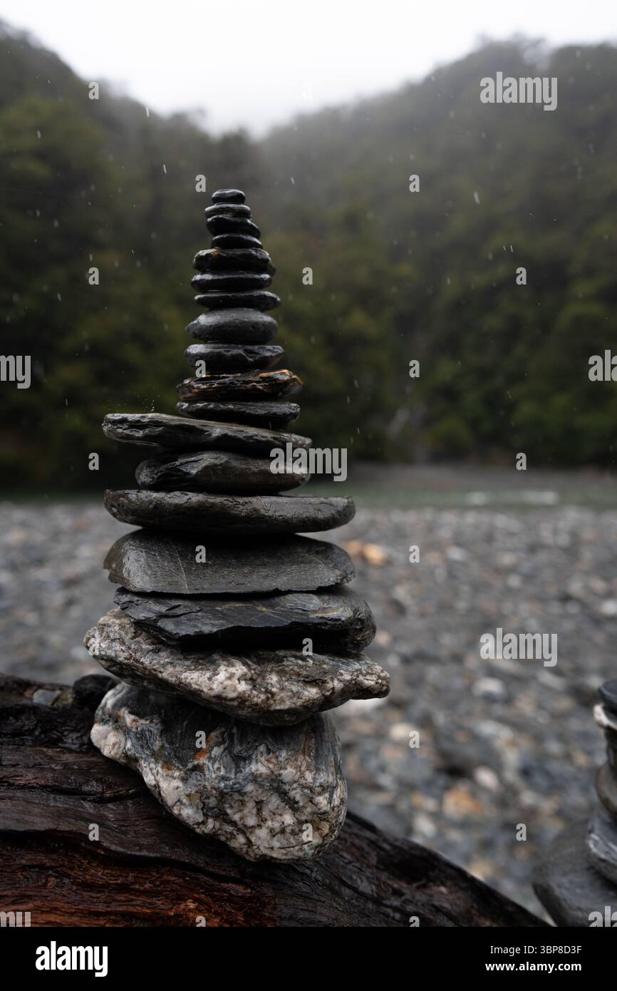 Una pila bilanciata di pietre piane poggia su una foresta di sabbia nebbiosa. Le pietre accuratamente disposte simboleggiano l'armonia, pa Foto Stock
