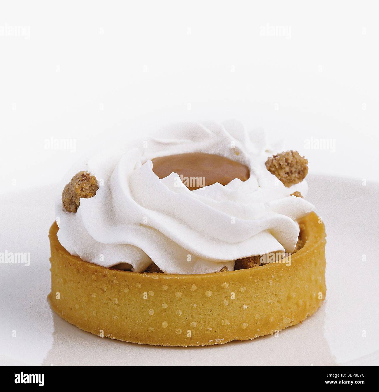 Cibo, tartette gourmet condite con panna montata e noci, presentate su un piatto bianco incontaminato su sfondo bianco Foto Stock
