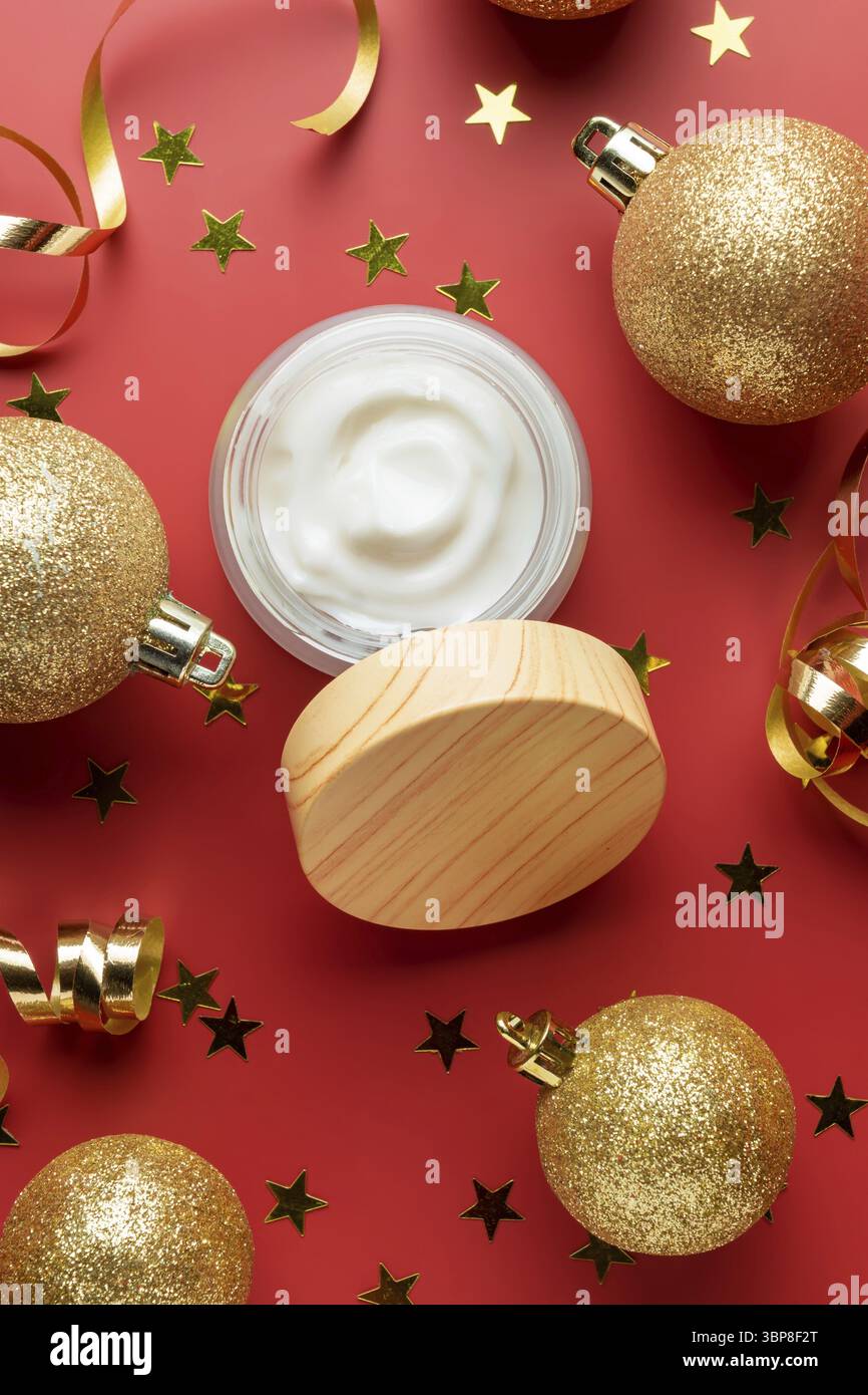 Vaso aperto bianco senza marchio con crema o maschera viso sullo sfondo festivo rosso Capodanno. Presentazione dei trattamenti di bellezza per le vacanze in regalo Foto Stock