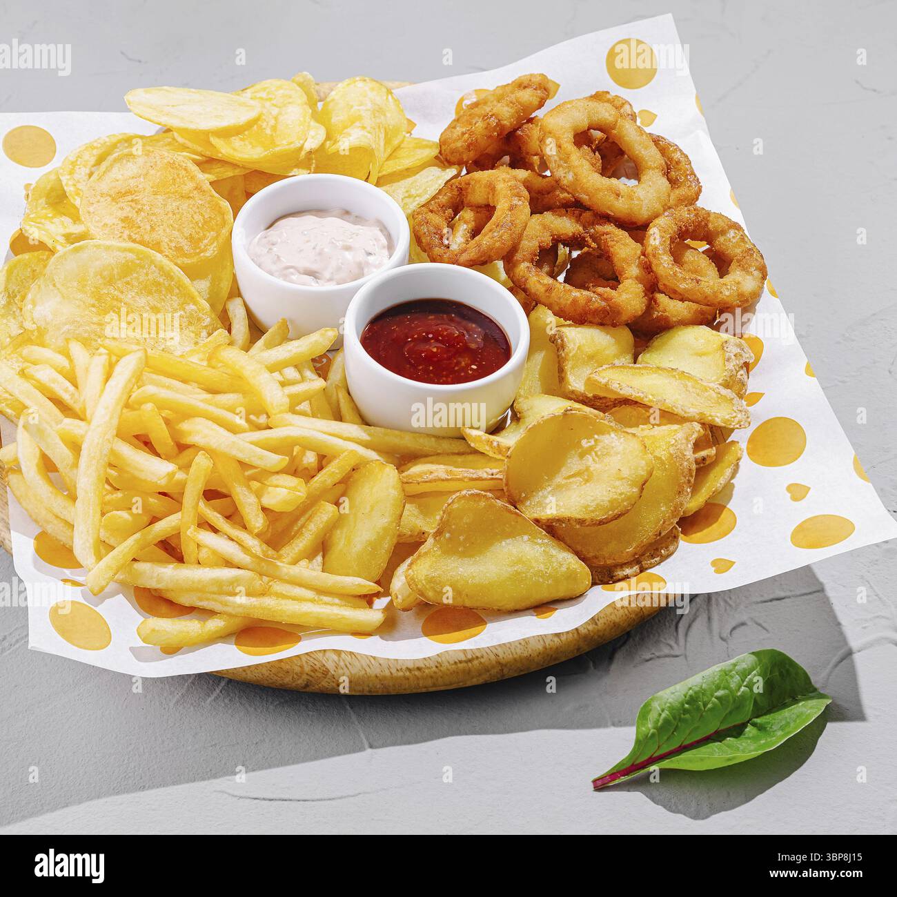 Cibo, Un piatto colorato offre una varietà di spuntini, tra cui patatine fritte croccanti, anelli di cipolla, patatine fritte e salse da immersione, disposte in modo attraente Foto Stock