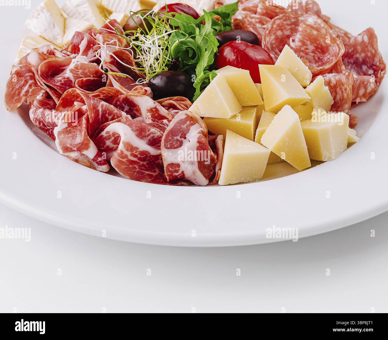 Cibo, salumi assortiti e cubetti di formaggio presentati elegantemente su un piatto bianco Foto Stock