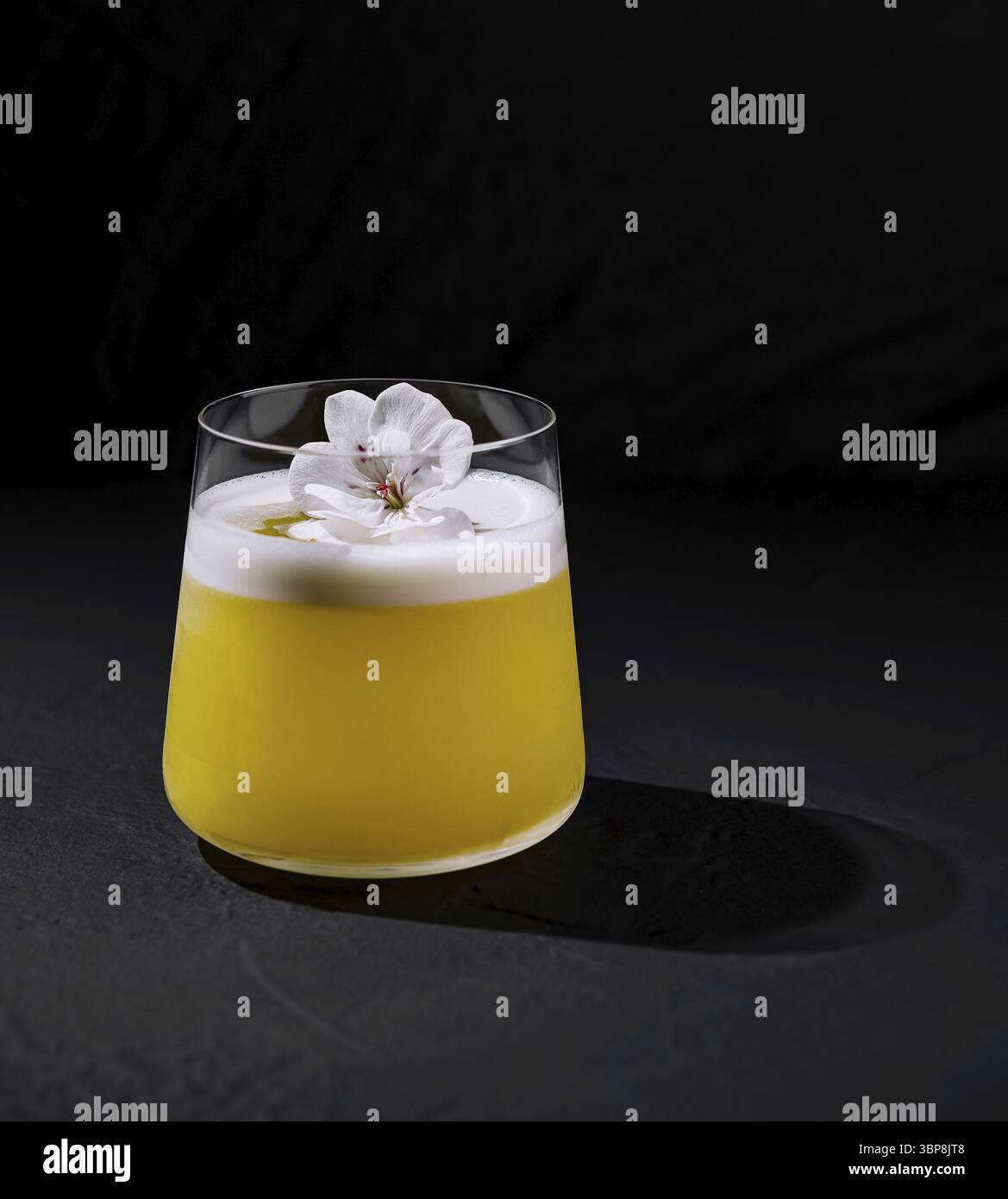 Cibo, cocktail sofisticato adornato da una decorazione floreale bianca su uno sfondo scuro Foto Stock