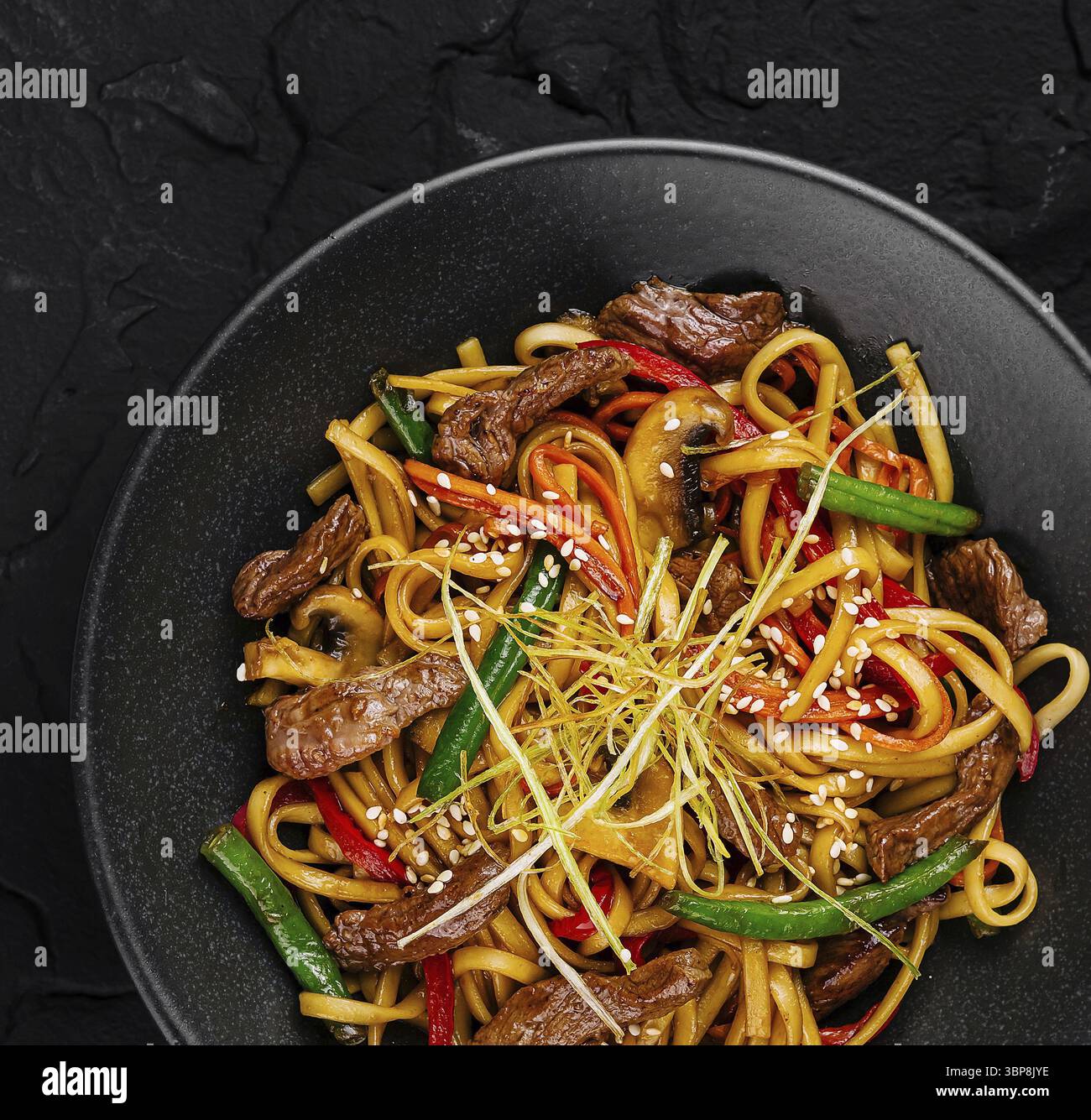 Cibo, vista dall'alto di deliziosi spaghetti saltati con manzo e verdure, guarniti con semi di sesamo Foto Stock