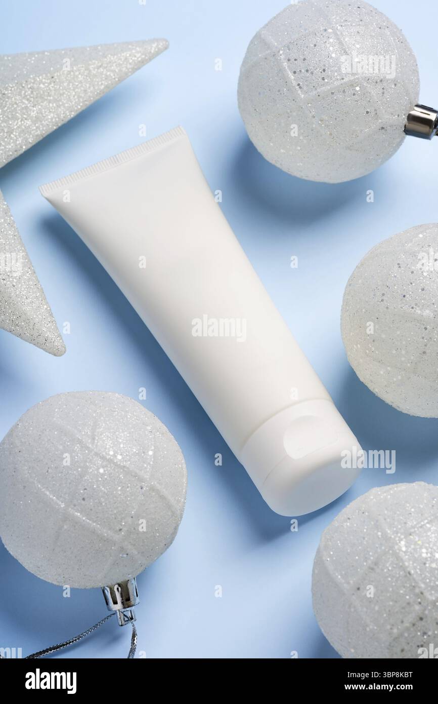 Tubo di plastica bianco senza marchio con crema o maschera viso su sfondo festivo blu anno nuovo. Presentazione dei trattamenti di bellezza per le vacanze in regalo Foto Stock