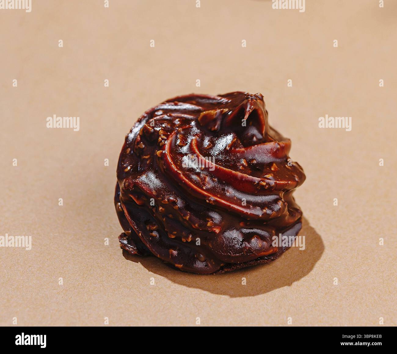 Cibo, elegante vortice di cioccolato lucido allestito su una superficie beige con un'estetica minimalista Foto Stock