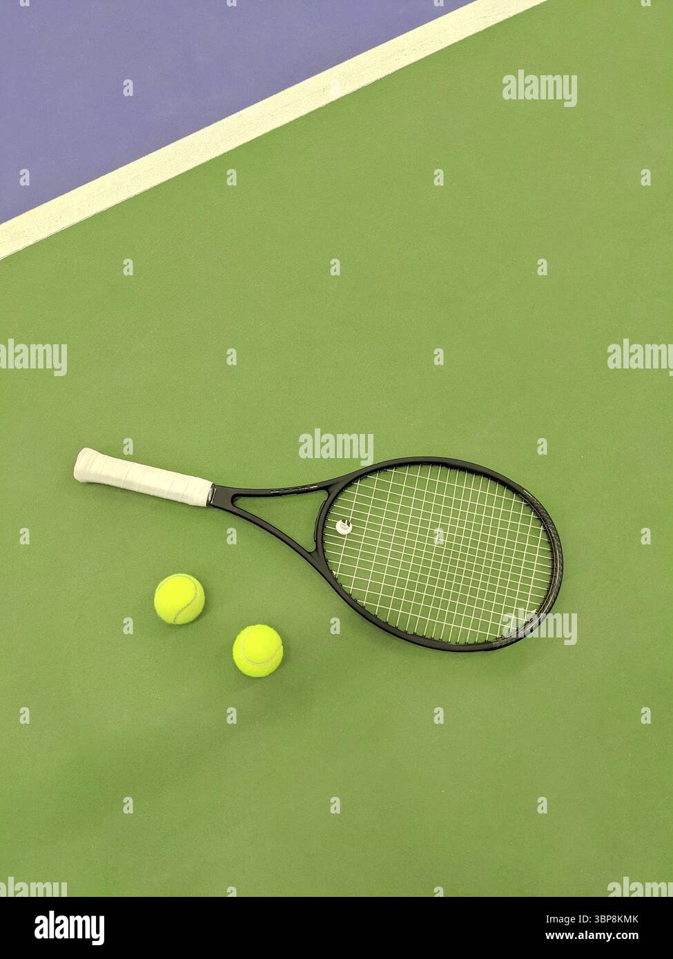 Vista dall'alto della racchetta da tennis e due palline sul campo da tennis in argilla verde Foto Stock