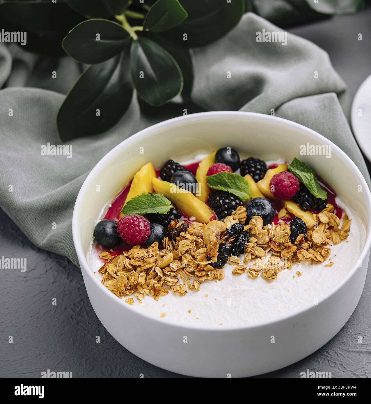Cibo, nutriente ciotola di yogurt con muesli e frutti di bosco abbinata su uno sfondo grigio minimalista Foto Stock