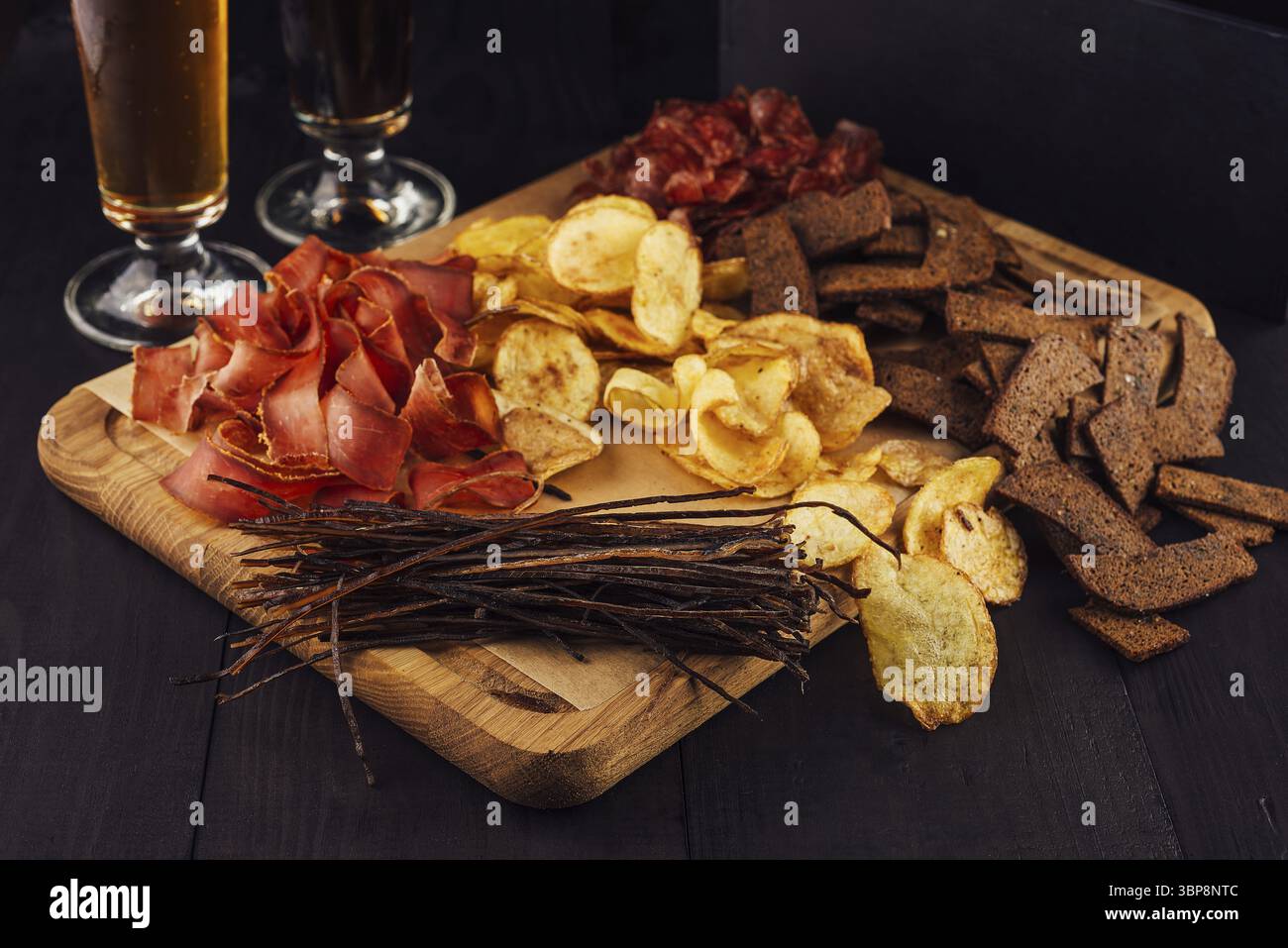 Cibo, deliziose patatine fritte, spuntini di carne e pesce secco steso su una tavola di legno, spuntini perfetti per la birra Foto Stock