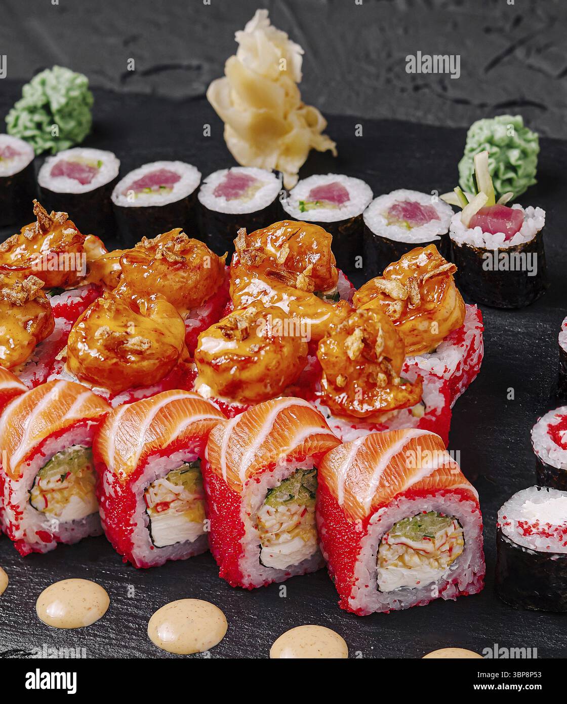 Cibo, Un piatto vibrante offre una varietà di sushi roll dai colori vivaci, tra cui gamberi e tonni preparati. Il piatto è disposto con artisteria Foto Stock