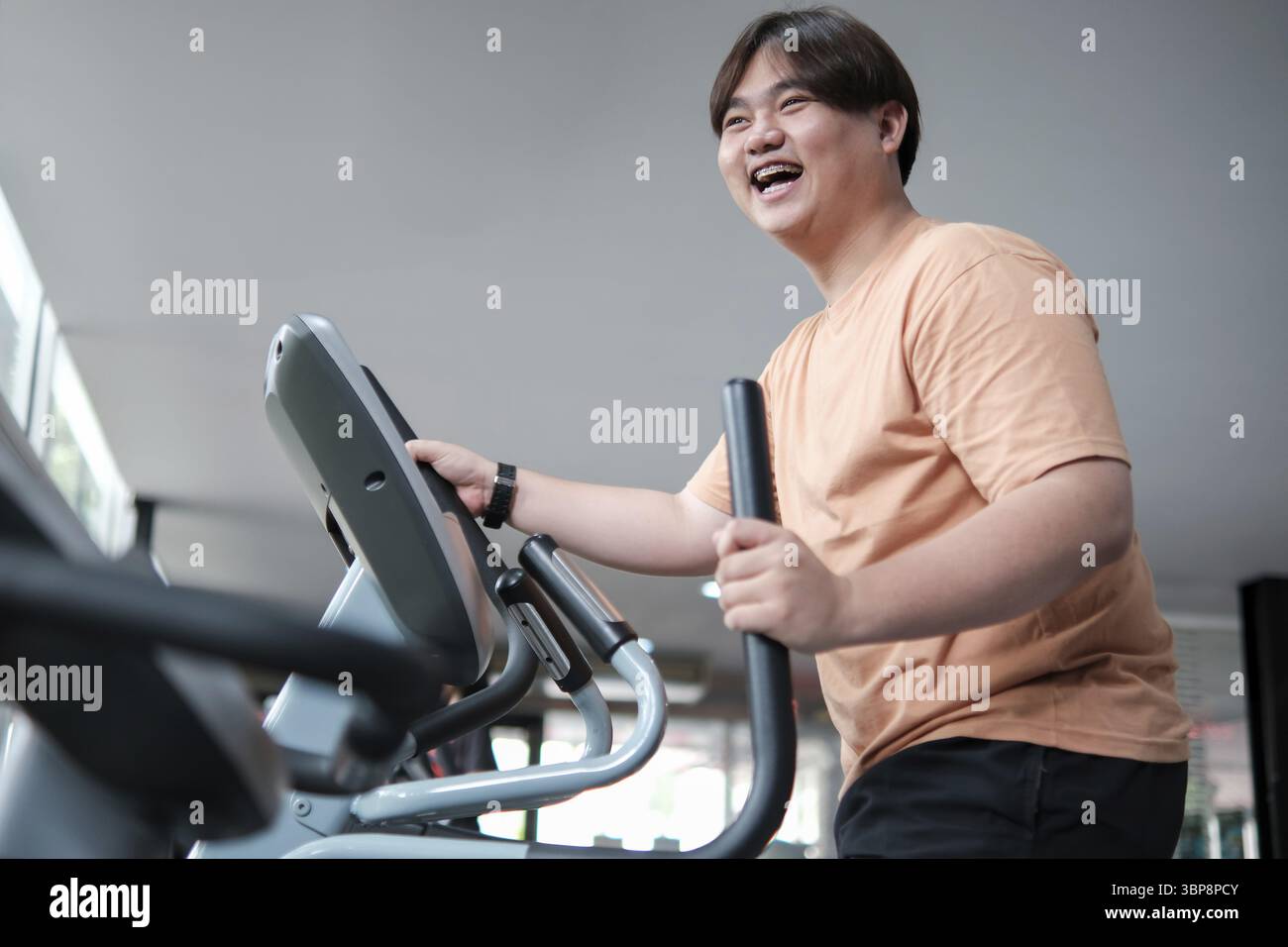 Un uomo sorride mentre guida una cyclette in palestra. Concetto di positività e motivazione, mentre l'uomo si sta divertendo e si sta prendendo cura di lui Foto Stock