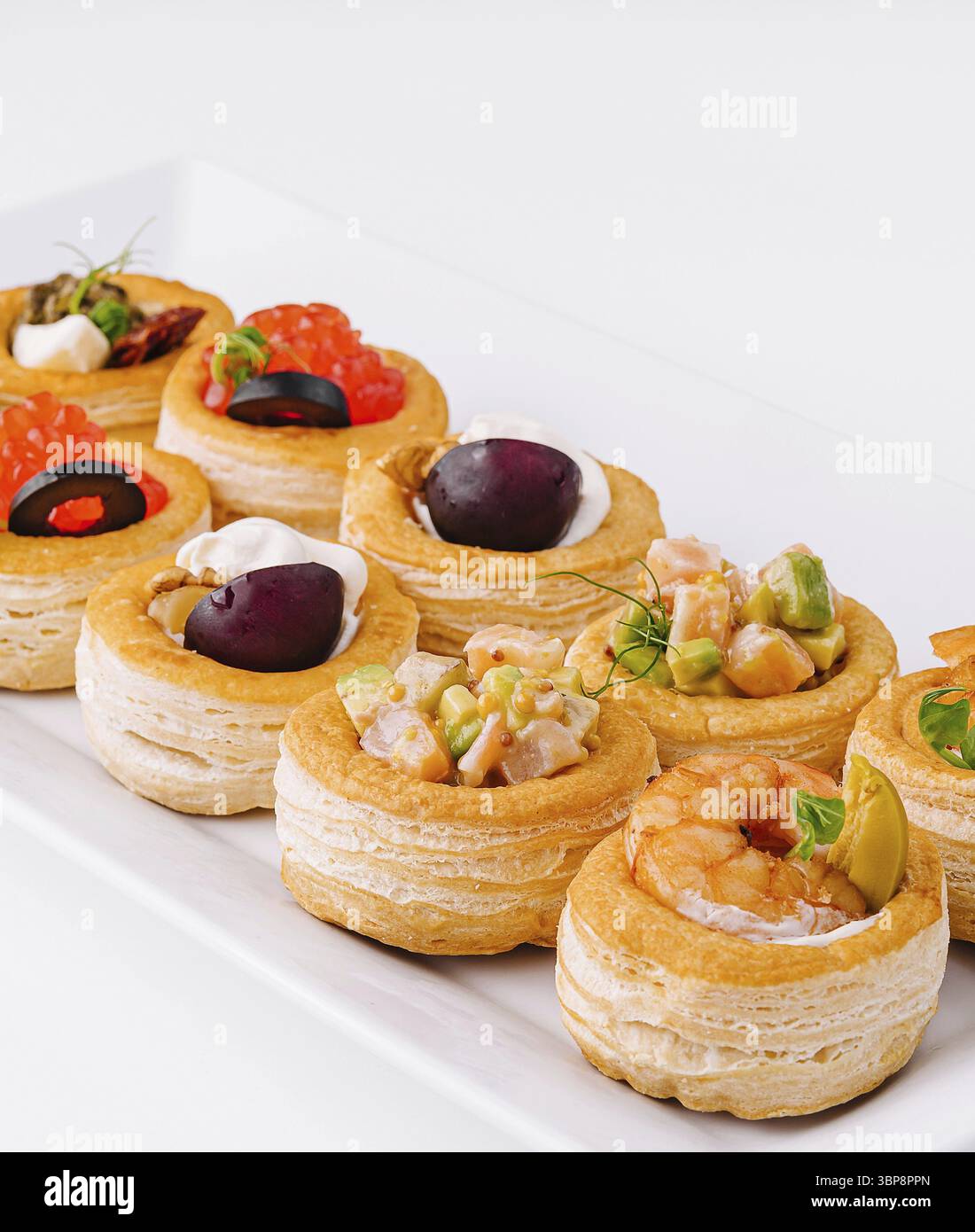 Cibo, selezione di eleganti mini tartine con condimenti salati su un elegante piatto bianco Foto Stock