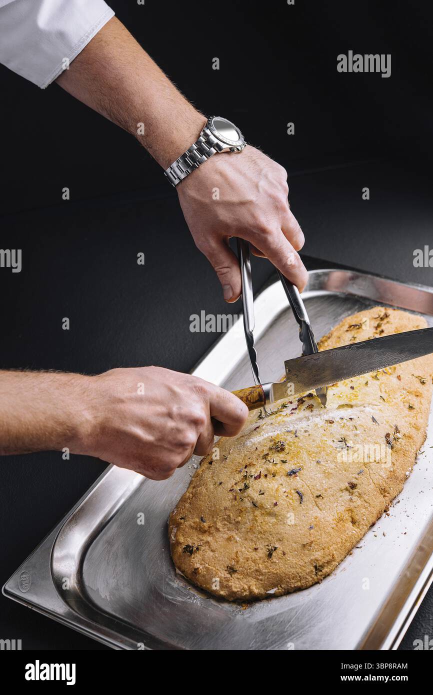 Cibo, pesce al forno, ripieno di erbe aromatiche, in crosta di sale tagliate da chef Foto Stock