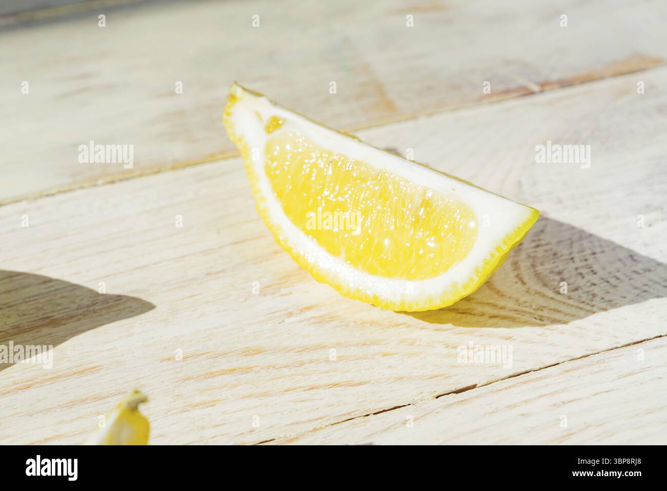 Primo piano di un quarto di limone su un tavolo di legno. Ombre dure in una giornata buia Foto Stock