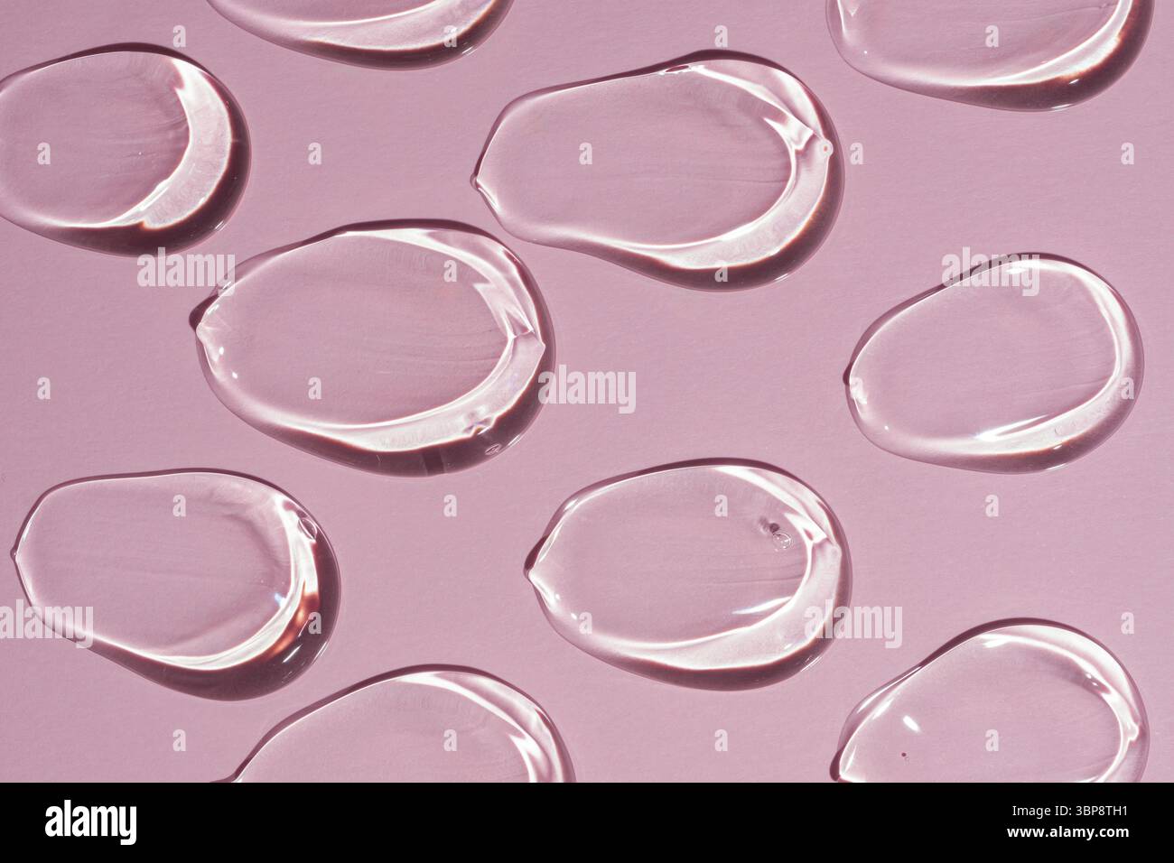 Il motivo cosmetico dei campioni di siero di alta qualità si riflette su una superficie liscia creando un'estetica pulita e moderna per i concetti di bellezza Foto Stock