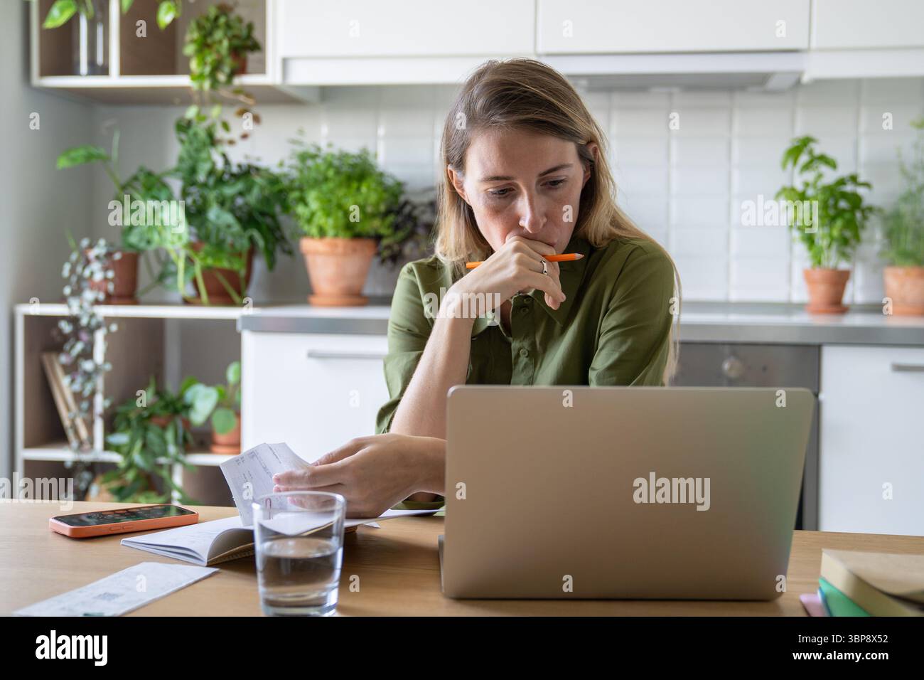 Triste donna contemplativa che esamina le bollette sul portatile. Gas a pagamento scaduto, elettricità, difficoltà finanziarie Foto Stock