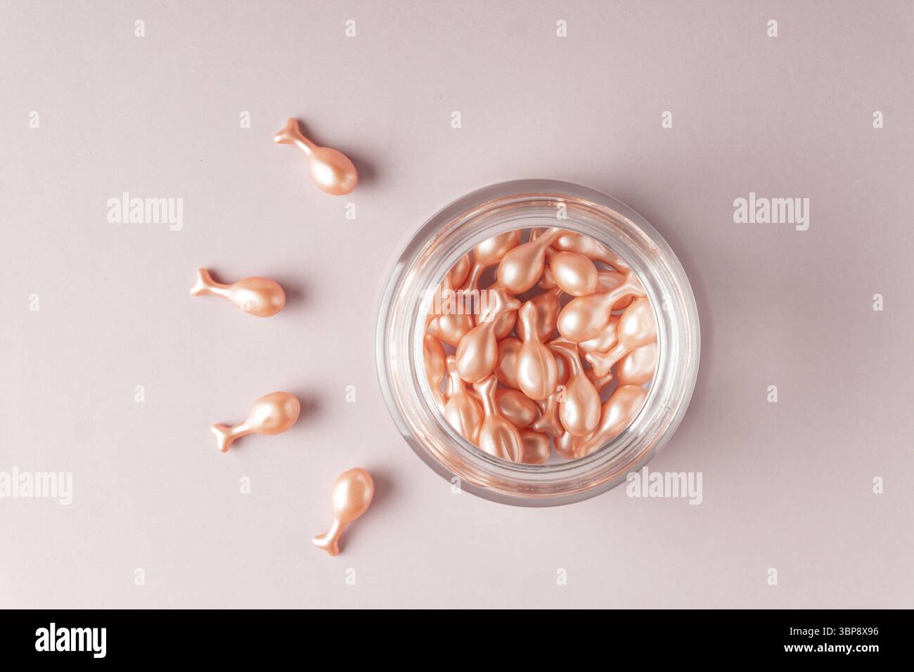 Capsule di olio per la cura del viso su sfondo rosa. olio nutriente monouso per pelle secca e danneggiata. Cosmetici anti-invecchiamento Foto Stock