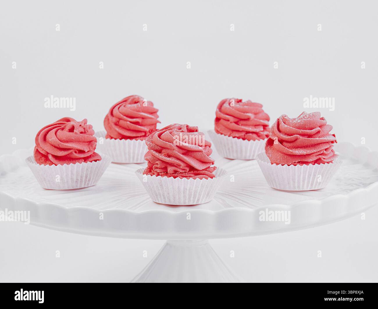 Cibo, elegante esposizione di sei cupcake di velluto rosso con glassa di formaggio cremoso su un supporto per torte bianco Foto Stock