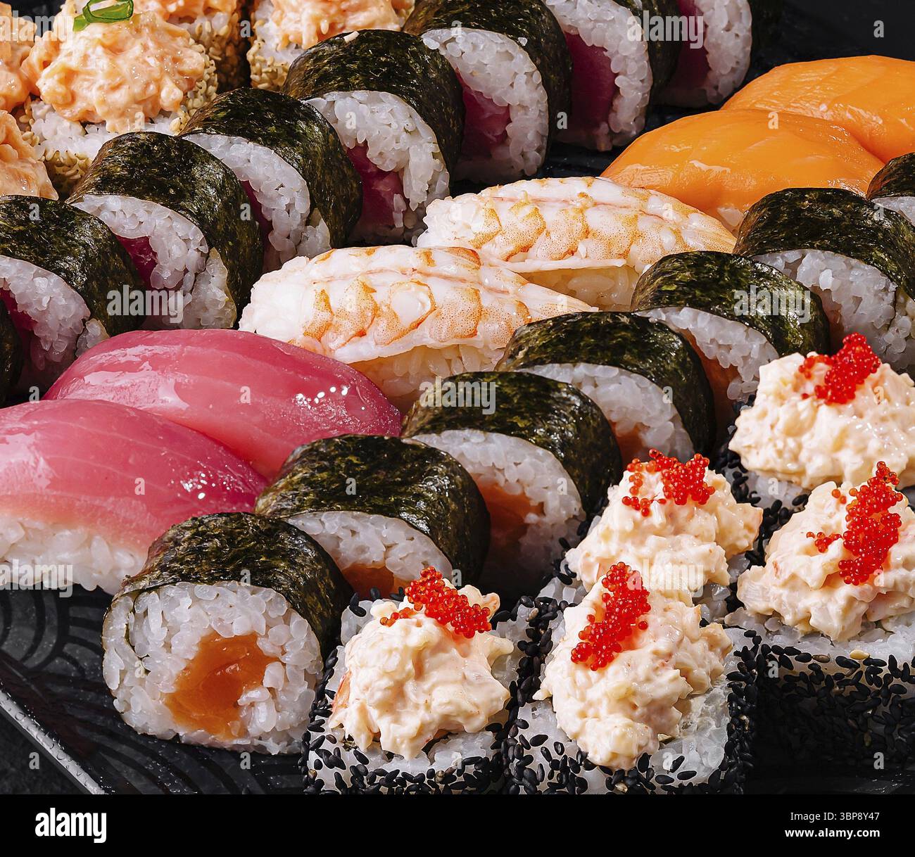 Cibo, deliziosa varietà di sushi roll serviti su un'ardesia nera, perfetto per un concetto di cucina giapponese Foto Stock