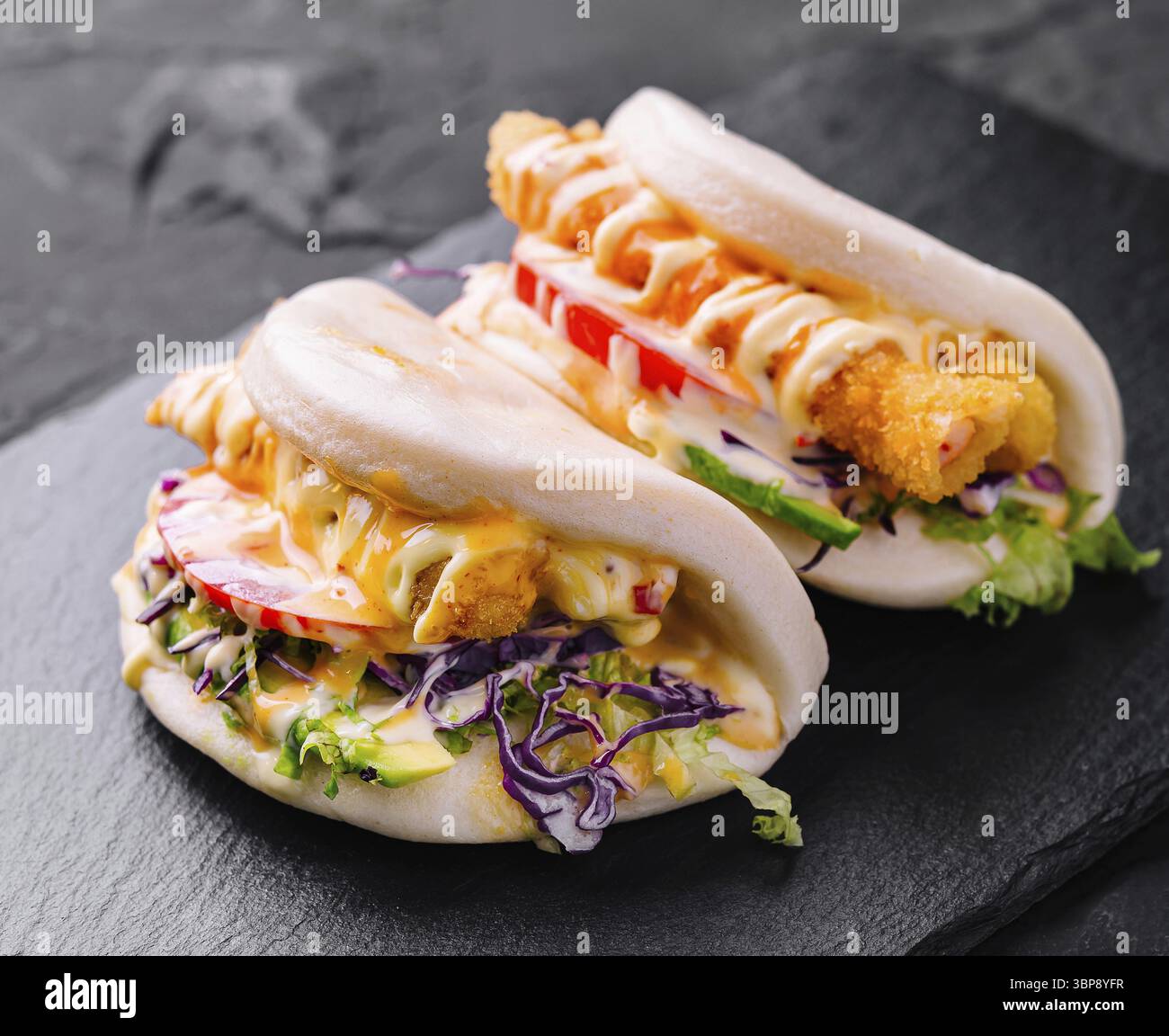 Cibo, gustosi panini di pollo bao serviti su un piatto di ardesia, perfetti per i menu della moderna cucina asiatica Foto Stock