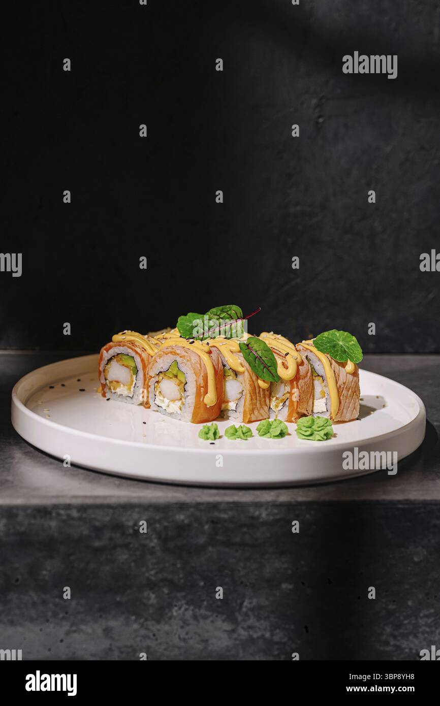 Cibo, sushi roll sono elegantemente disposti su un piatto minimalista, completato da erbe fresche. Lo sfondo moderno della cucina esalta l'appetitoso prese Foto Stock