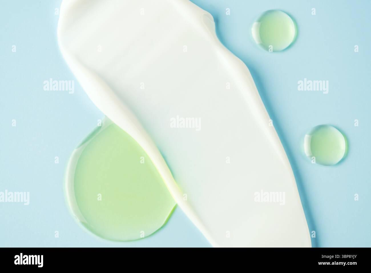 Macchie di consistenza cremosa sui prodotti cosmetici su sfondo blu. La crema per il viso e le gocce di olio essenziale si avvicinano da vicino Foto Stock