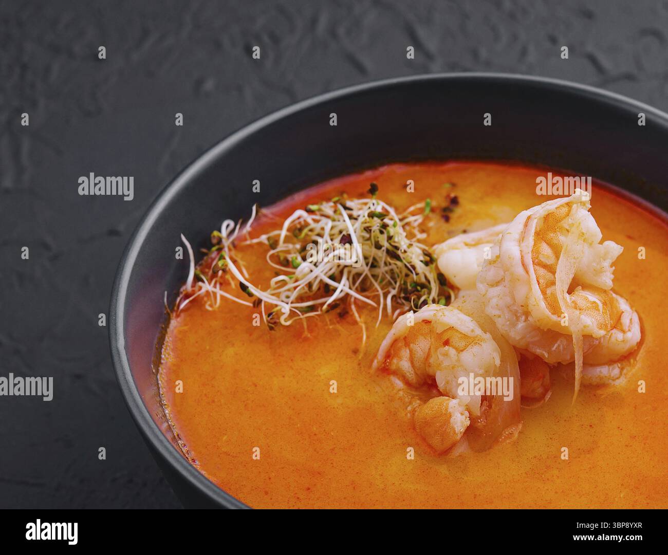 Cibo, tradizionale zuppa tailandese Tom Yam in ciotola nera Foto Stock