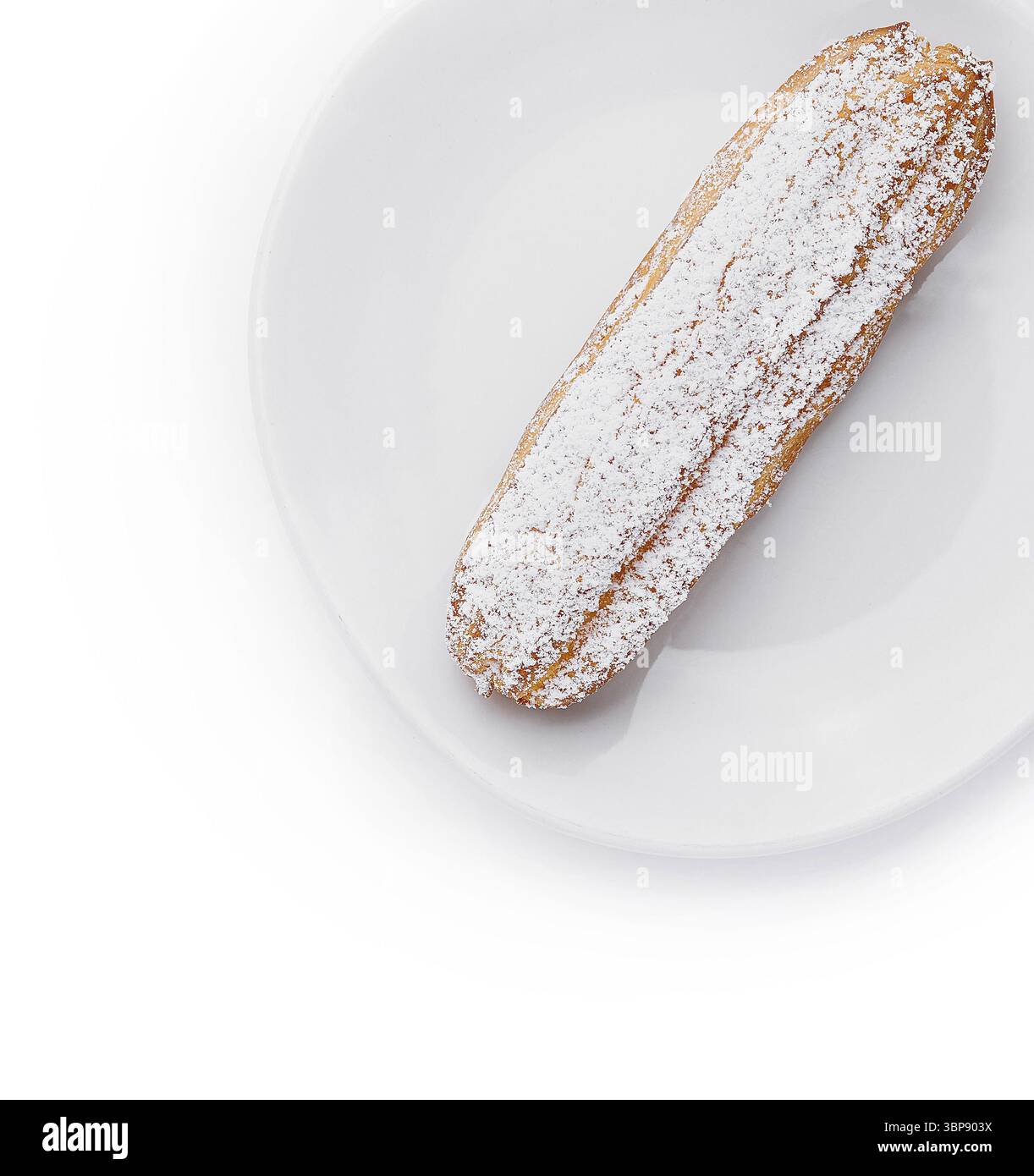 Cibo, eclair appetitoso spolverato con zucchero a velo servito su un piatto bianco immacolato Foto Stock