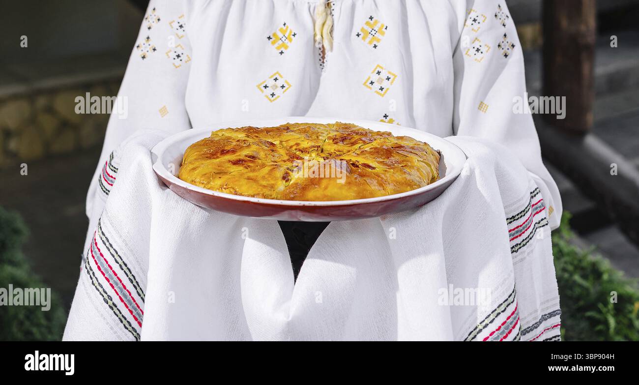 Cibo, la persona in costume popolare tiene una torta fatta in casa, mostrando cucina culturale Foto Stock