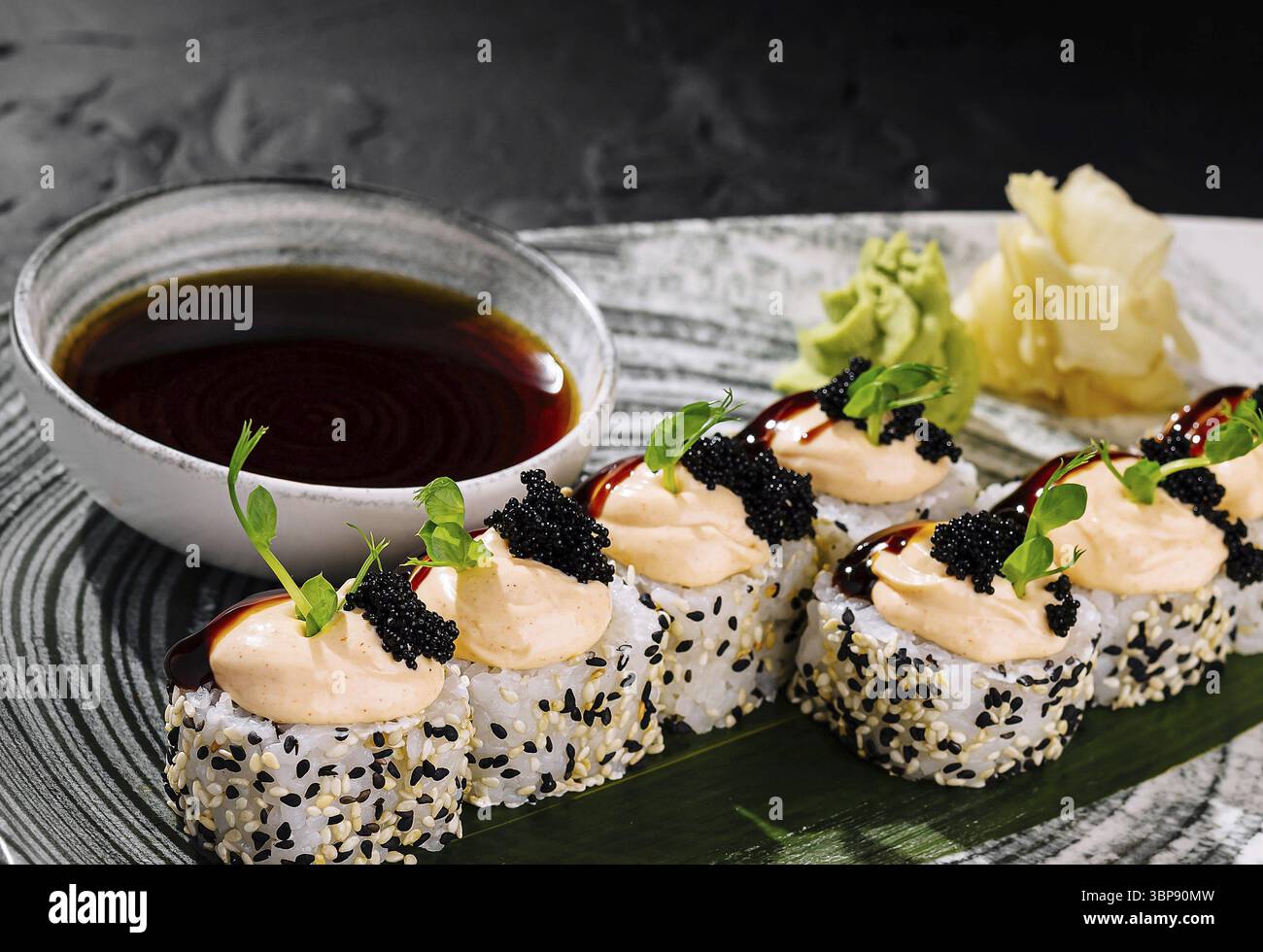 Cibo, elegante sushi roll ricoperto di caviale, servito con salsa di soia su un piatto elegante Foto Stock
