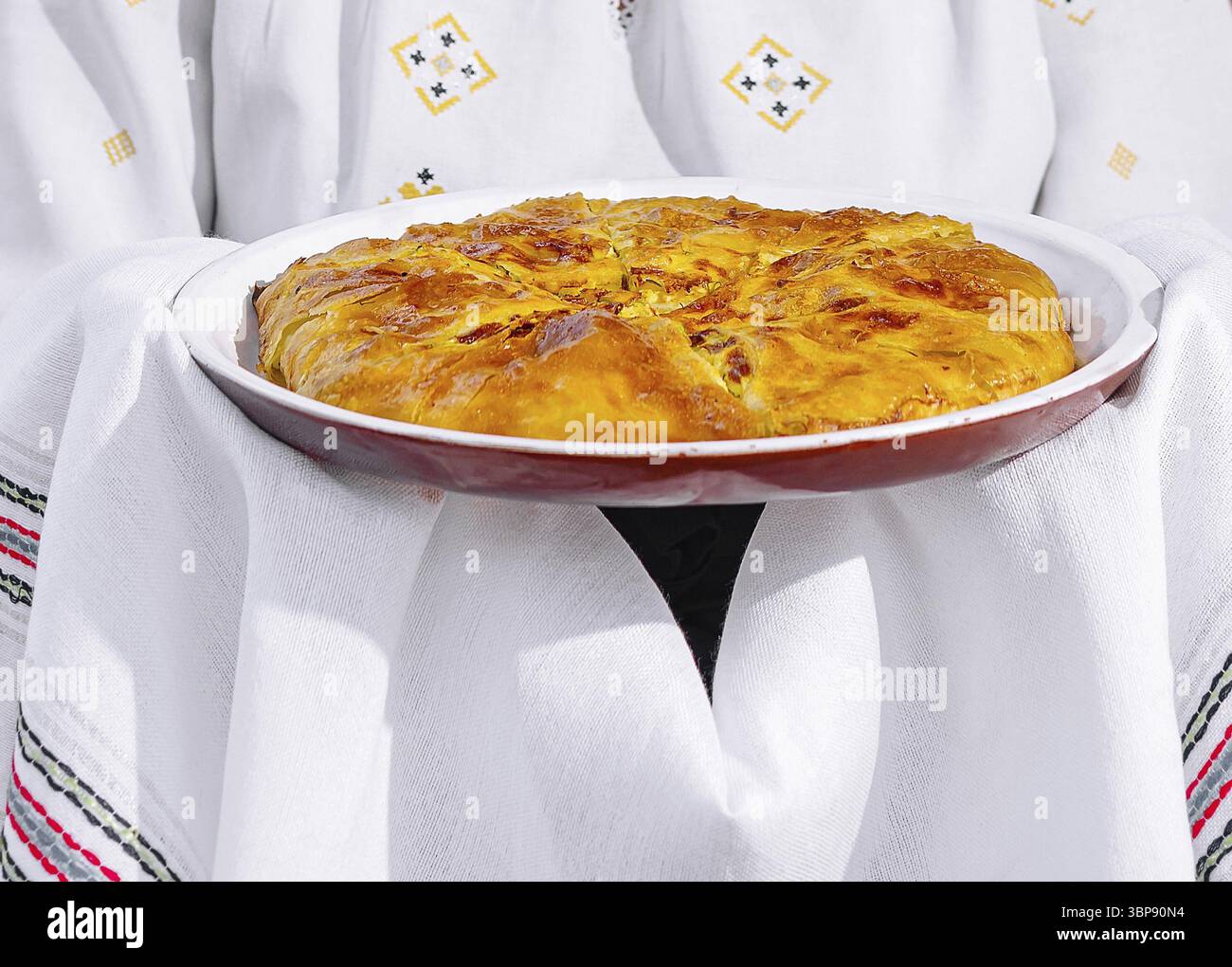 Cibo, la persona in costume popolare tiene una torta fatta in casa, mostrando cucina culturale Foto Stock