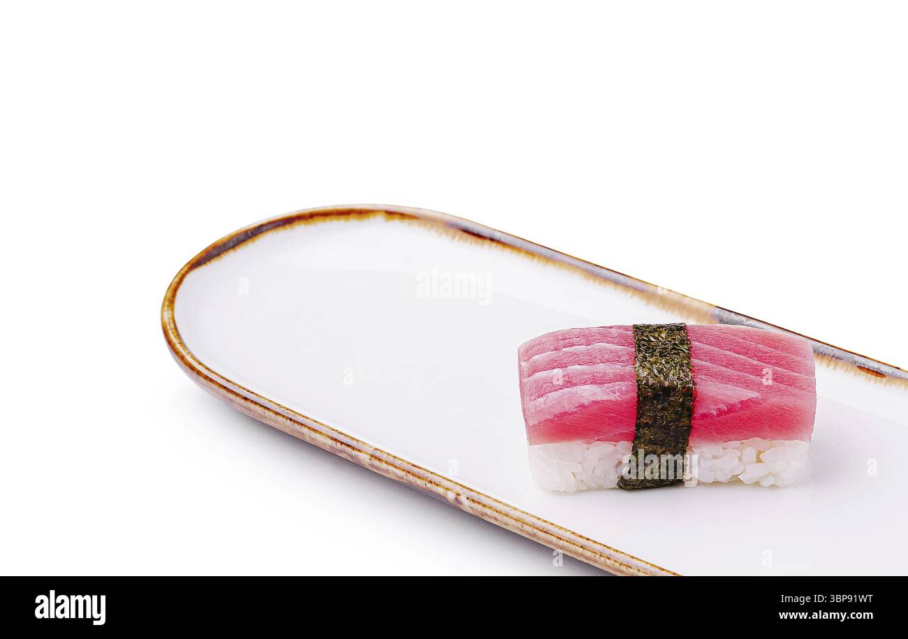 Cibo, Un pezzo di sushi con tonno fresco avvolto in alghe poggia su un elegante piatto bianco. La presentazione mette in evidenza i colori vivaci e le delizie Foto Stock
