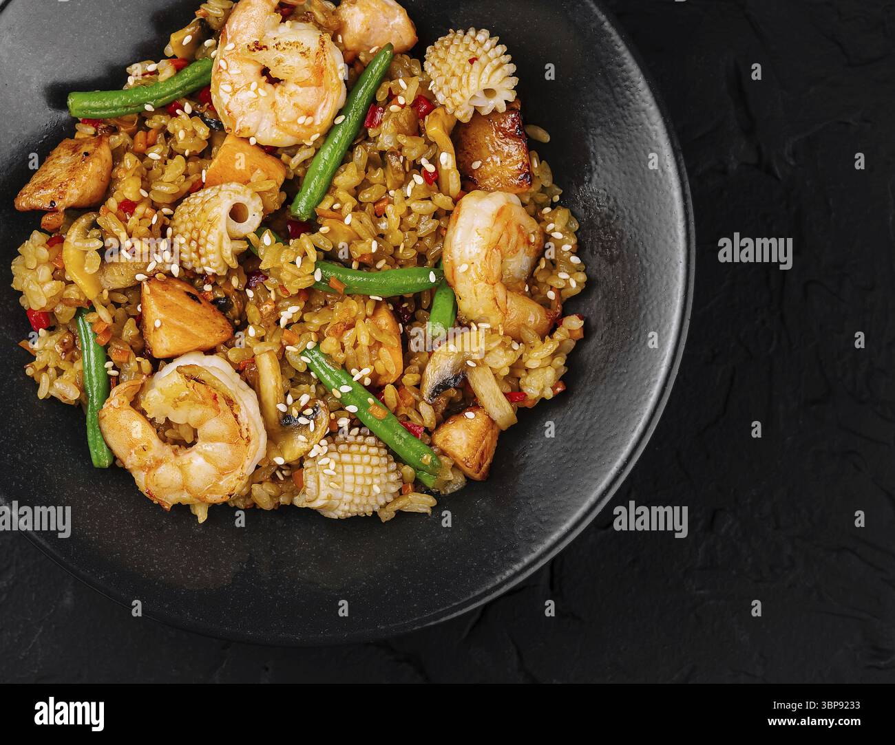 Cibo, vista dall'alto di un saporito gamberetto fritto con verdure miste e riso servito su un piatto scuro Foto Stock