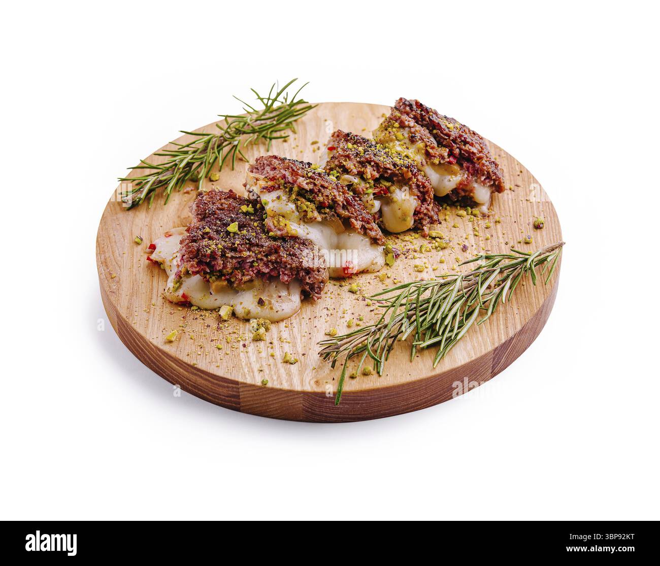 Cibo, Una tavola di legno mostra tre dolci ripieni splendidamente disposti con noci schiacciate ed erbe aromatiche. La presentazione evidenzia la trama e. Foto Stock