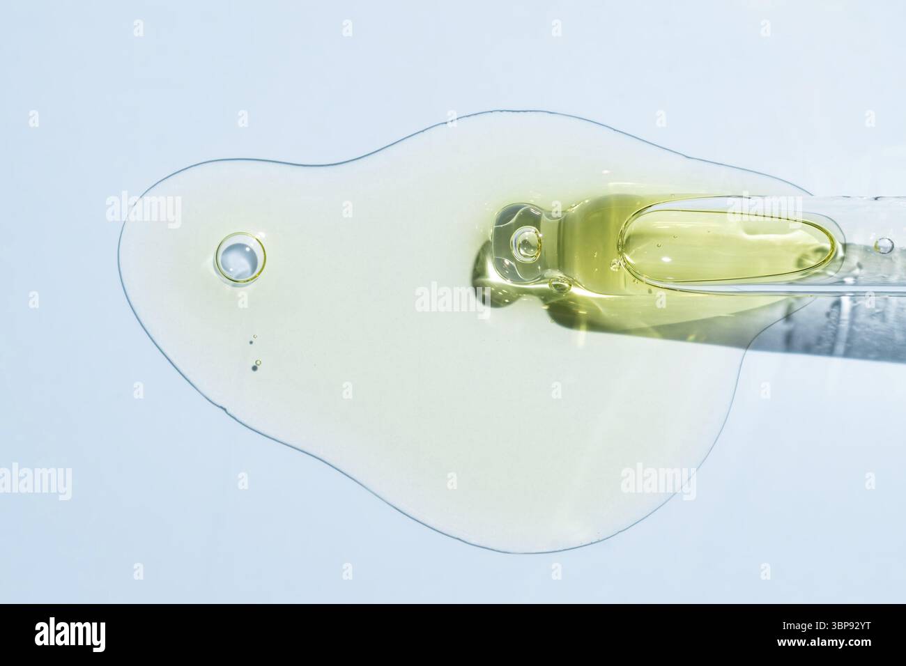 Primo piano della pipetta con il versamento di siero liquido e ombre su sfondo blu. Cosmetici alla moda con ombre dure Foto Stock