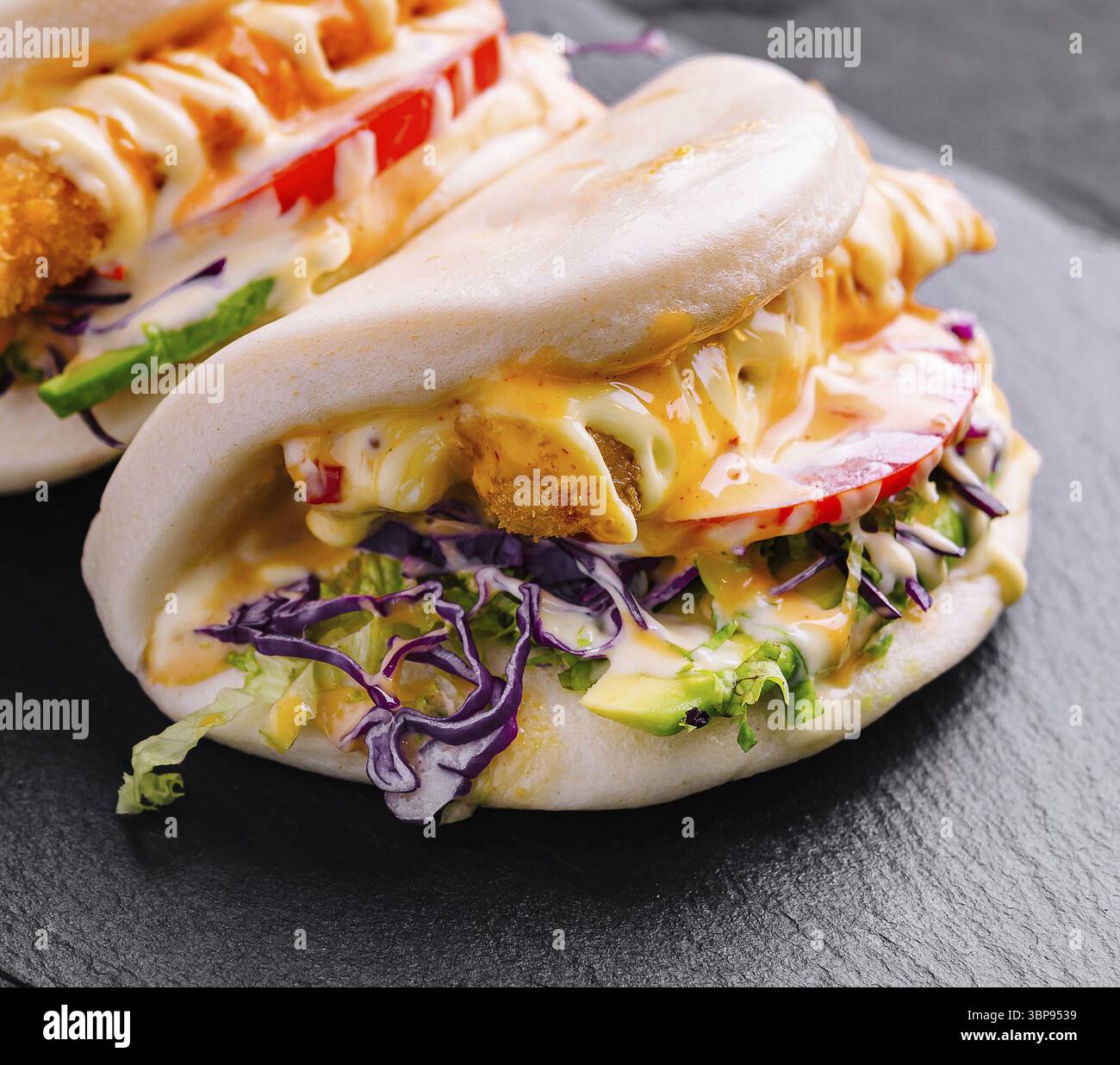 Cibo, gustosi panini di pollo bao serviti su un piatto di ardesia, perfetti per i menu della moderna cucina asiatica Foto Stock