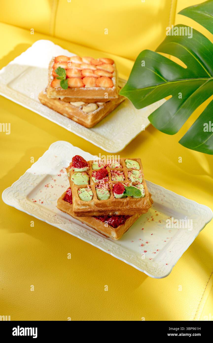 waffle belgi con fragole su sfondo giallo Foto Stock