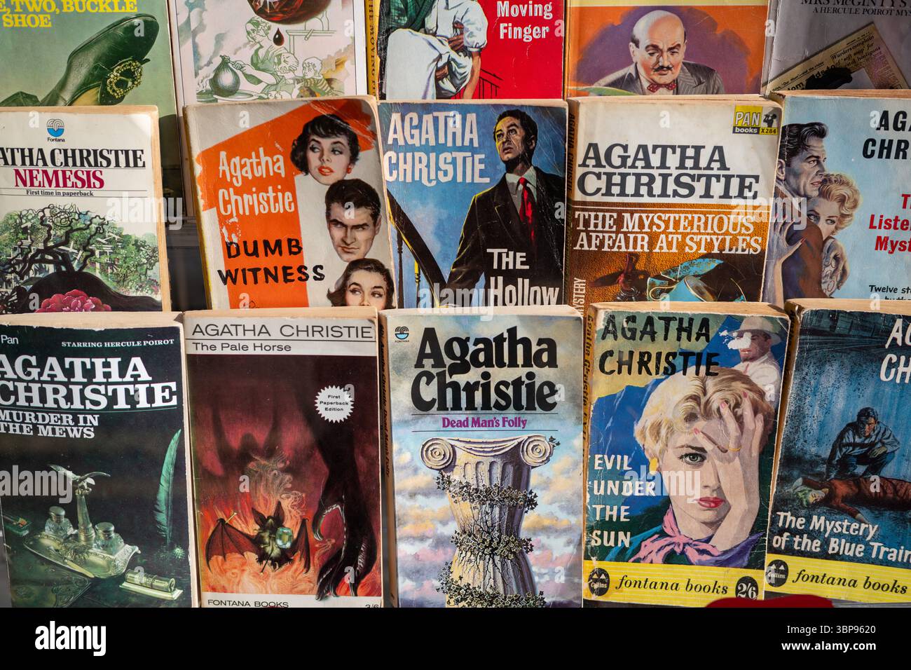 Una colorata collezione di romanzi in brossura vintage di Agatha Christie esposti fianco a fianco, che mostrano copertine e titoli classici della narrativa poliziesca. Foto Stock