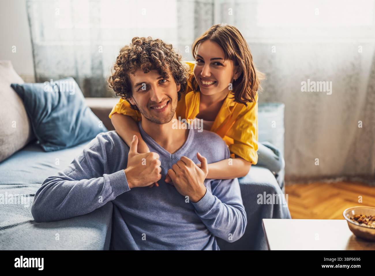 Ritratto di una giovane coppia felice a casa. Guardano la telecamera e sorridono. Foto Stock