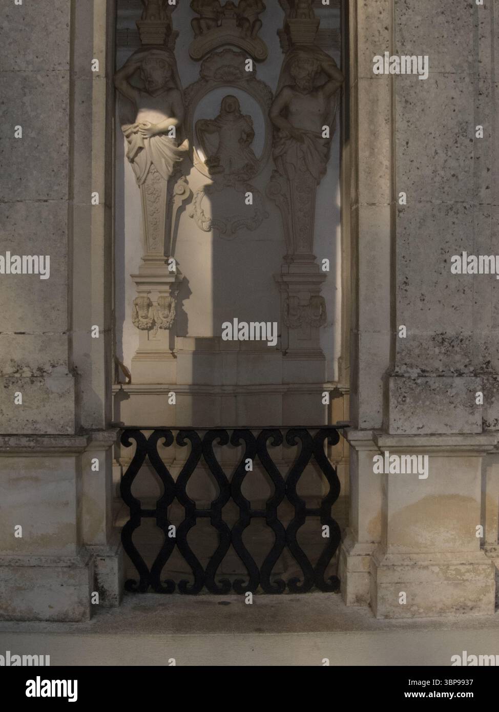 Un'immagine dettagliata di un'alcova in pietra con sculture e una ringhiera decorativa in ferro. L'alcova presenta due figure scolpite che fiancheggiano un rilievo centrale, A. Foto Stock